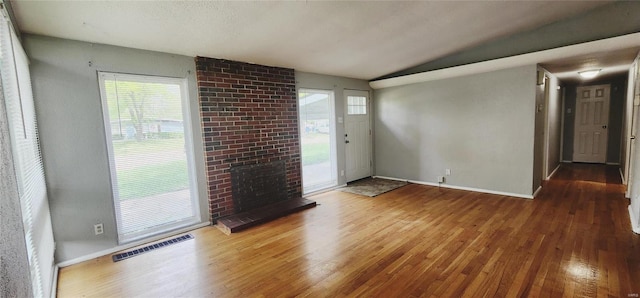 spare room featuring hardwood / wood-style flooring, a brick fireplace, and vaulted ceiling