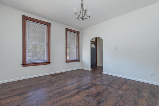 empty room featuring a notable chandelier and dark wood-type flooring