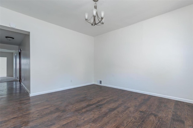 unfurnished room with a notable chandelier and dark hardwood / wood-style floors