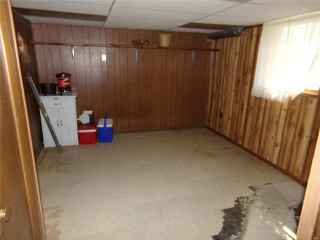 basement featuring wooden walls and a drop ceiling