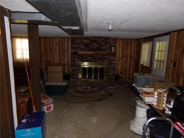 living room with wood walls, a brick fireplace, and concrete flooring