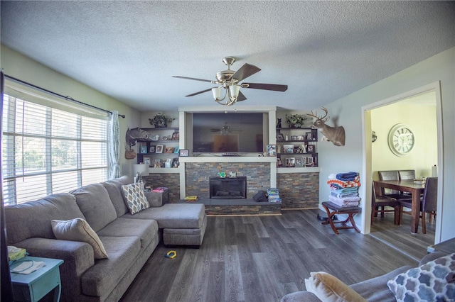 living room with ceiling fan, a fireplace, dark hardwood / wood-style floors, and a textured ceiling