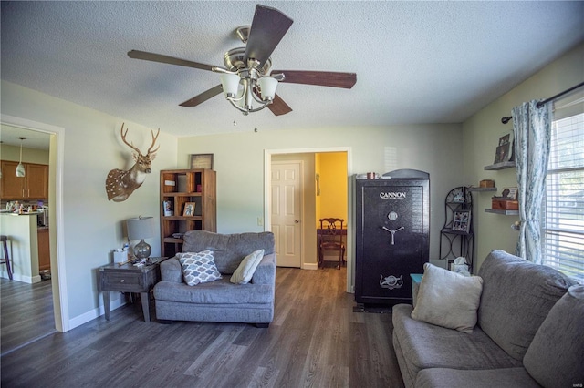 living room featuring a textured ceiling, dark wood-type flooring, and ceiling fan