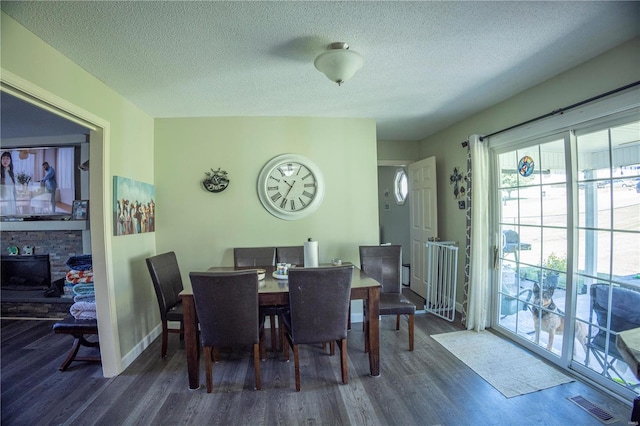 dining space featuring a textured ceiling, dark hardwood / wood-style flooring, and a fireplace