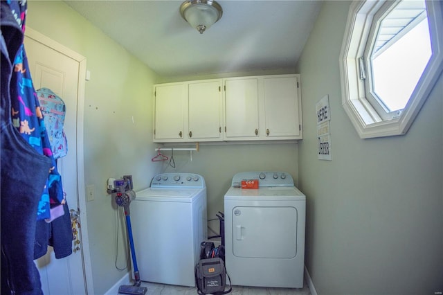 washroom with a skylight, a wealth of natural light, cabinets, and washing machine and clothes dryer