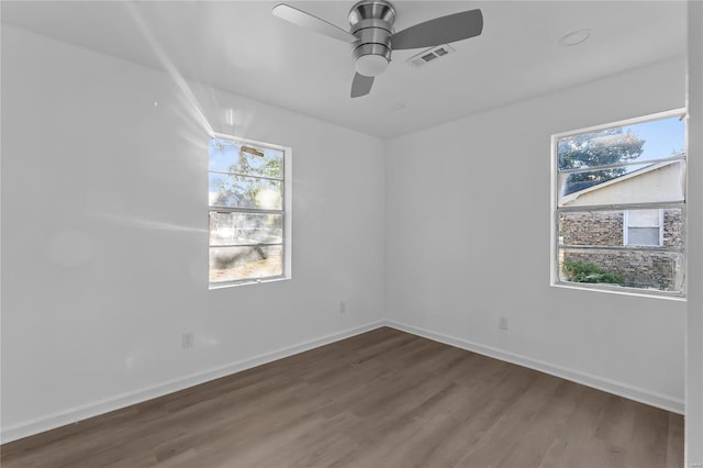 empty room featuring dark hardwood / wood-style floors, ceiling fan, and a wealth of natural light