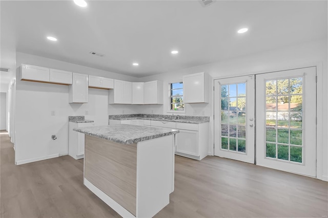 kitchen featuring a healthy amount of sunlight, french doors, a center island, and white cabinetry