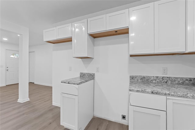 kitchen featuring white cabinetry, light stone counters, and light wood-type flooring