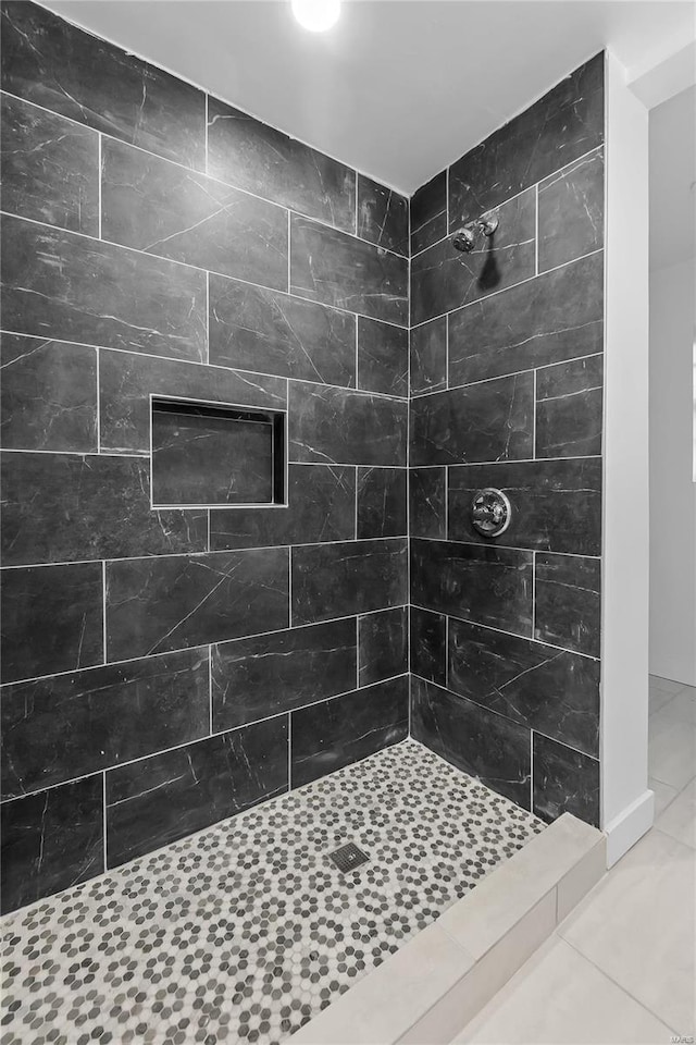 bathroom with a tile shower and tile patterned flooring