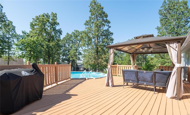 wooden deck featuring a fenced in pool, area for grilling, and a gazebo