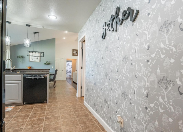 kitchen with tile patterned flooring, dishwasher, vaulted ceiling, sink, and a textured ceiling