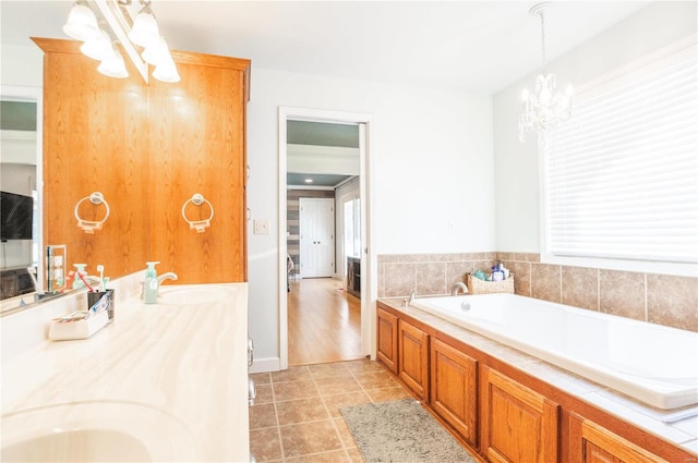 bathroom with tile patterned flooring, vanity, a notable chandelier, and a bath