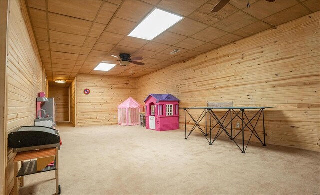 playroom featuring light colored carpet, ceiling fan, and wood walls