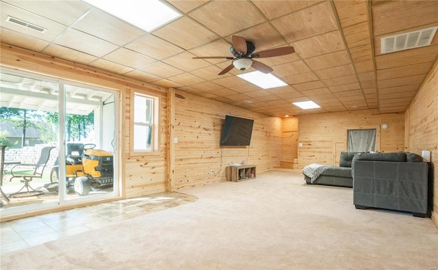 living room with carpet flooring, wood walls, and ceiling fan