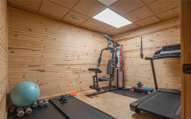 exercise room featuring wood walls and a paneled ceiling