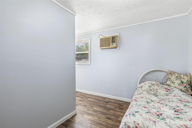 bedroom with a textured ceiling, crown molding, dark wood-type flooring, and a wall mounted air conditioner