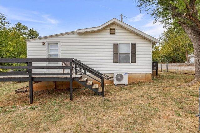 back of property with a deck, a yard, and ac unit