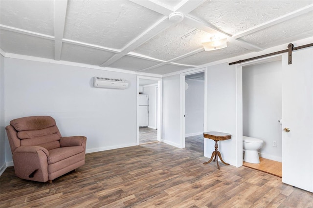 living area with a barn door, a textured ceiling, a wall unit AC, and hardwood / wood-style flooring