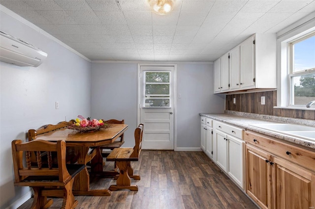 kitchen with crown molding, dark wood-type flooring, an AC wall unit, and white cabinetry