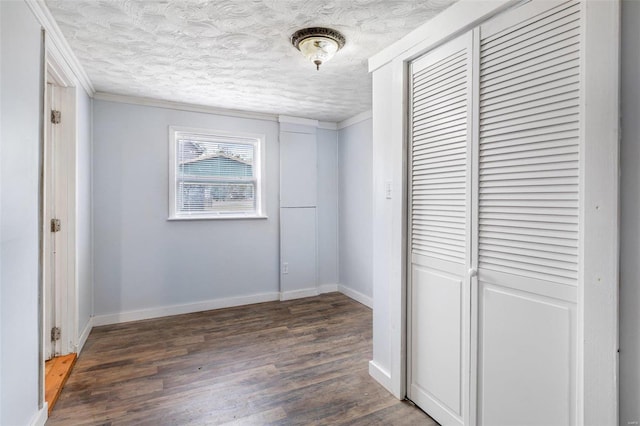 corridor featuring ornamental molding, a textured ceiling, and dark hardwood / wood-style floors