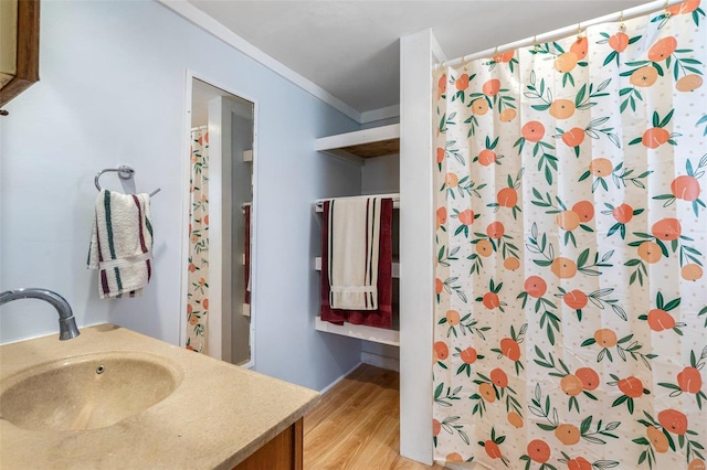 bathroom with wood-type flooring, vanity, and crown molding