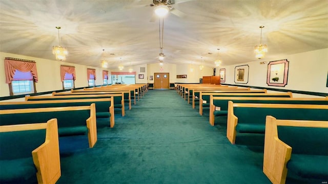 rec room with vaulted ceiling, dark colored carpet, and ceiling fan with notable chandelier