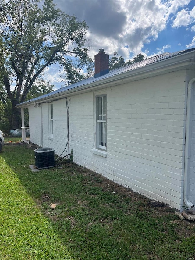 view of side of property with central air condition unit and a yard