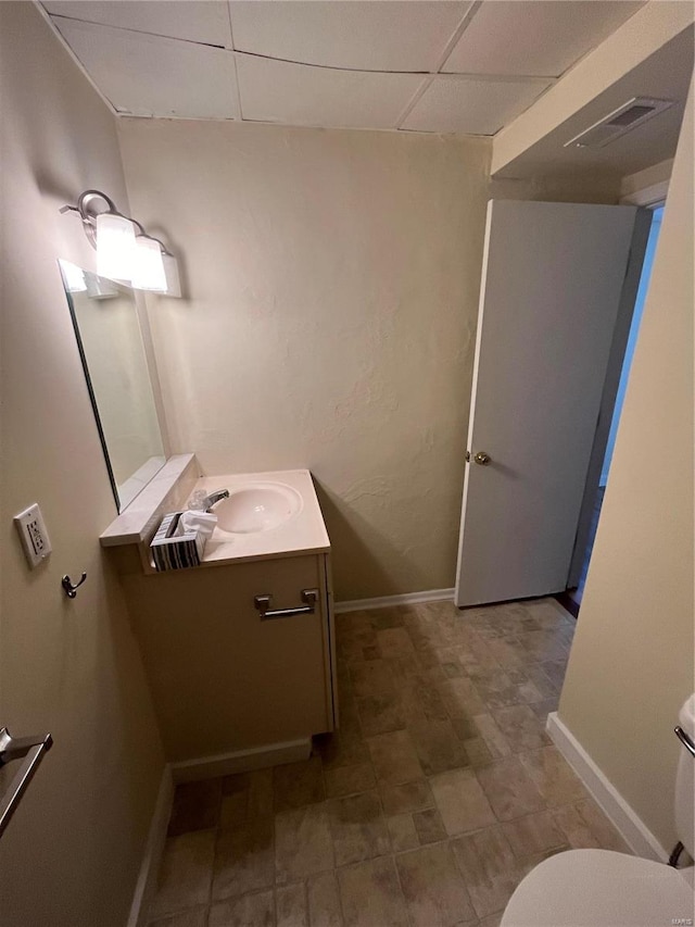 bathroom with vanity, toilet, and a paneled ceiling