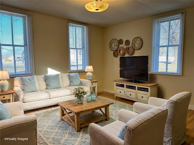 living area with plenty of natural light, baseboards, and wood finished floors