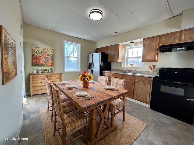 kitchen featuring visible vents, black electric range oven, fridge with ice dispenser, light countertops, and under cabinet range hood