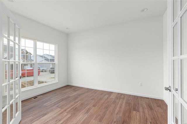 empty room featuring visible vents, baseboards, french doors, and light wood finished floors