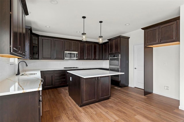 kitchen with a center island, decorative light fixtures, appliances with stainless steel finishes, sink, and wood-type flooring