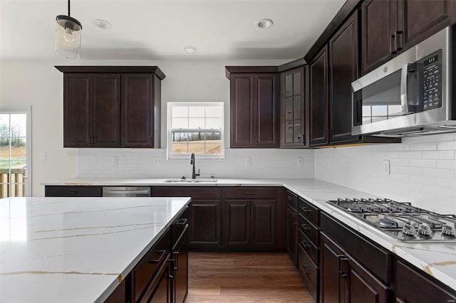 kitchen with stainless steel appliances, light stone counters, sink, decorative backsplash, and dark wood-type flooring