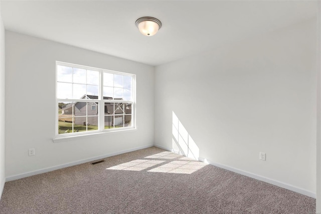 carpeted empty room featuring baseboards and visible vents