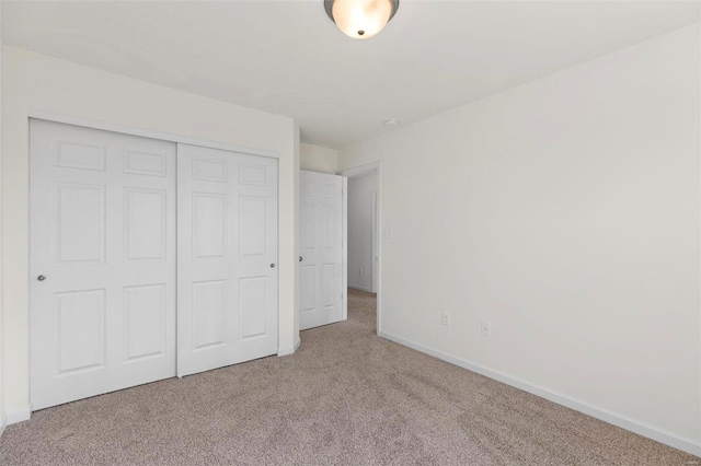 unfurnished bedroom featuring light carpet and a closet