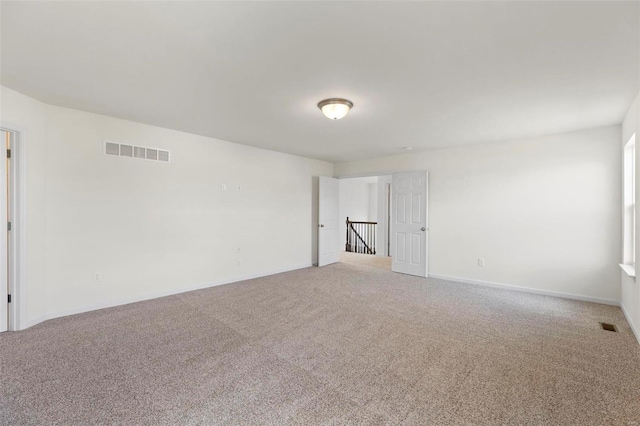 empty room featuring carpet, visible vents, and baseboards