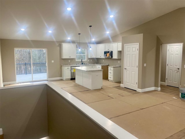 kitchen with white cabinets, a kitchen island, appliances with stainless steel finishes, decorative light fixtures, and vaulted ceiling