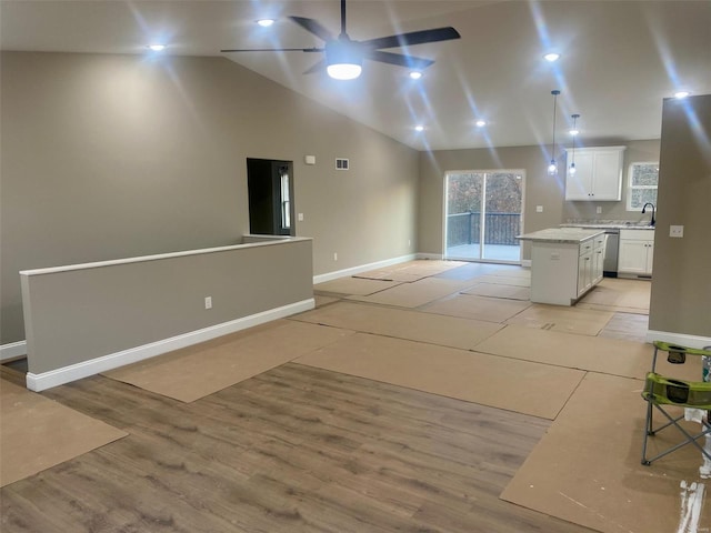 interior space featuring a kitchen island, open floor plan, light countertops, light wood-style floors, and white cabinetry