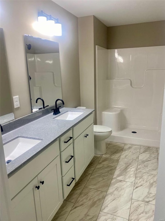 bathroom featuring marble finish floor, a sink, toilet, and double vanity