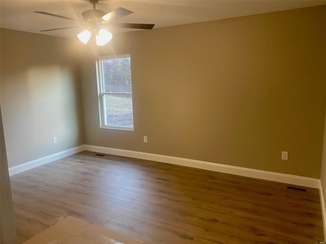 empty room featuring visible vents, ceiling fan, baseboards, and wood finished floors