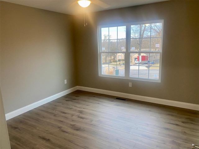 spare room featuring visible vents, baseboards, and wood finished floors