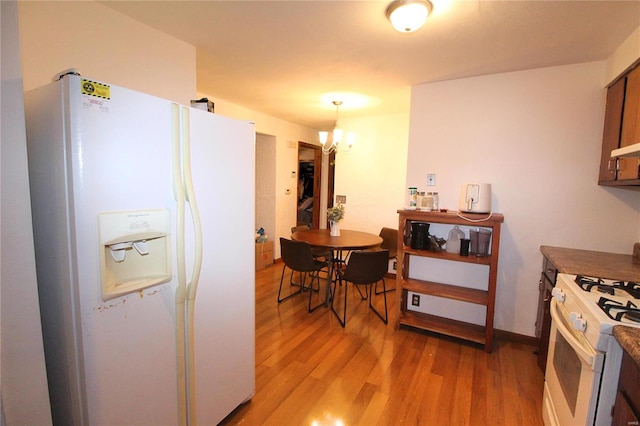 kitchen with light hardwood / wood-style flooring, pendant lighting, a notable chandelier, and white appliances