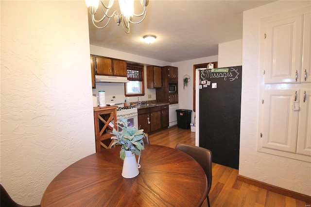 dining room with sink, a chandelier, and hardwood / wood-style flooring