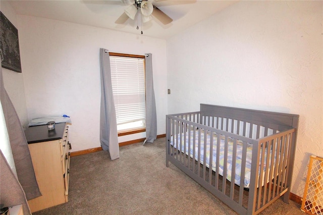 carpeted bedroom featuring ceiling fan and a nursery area