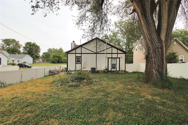 back of property featuring a lawn and a storage unit