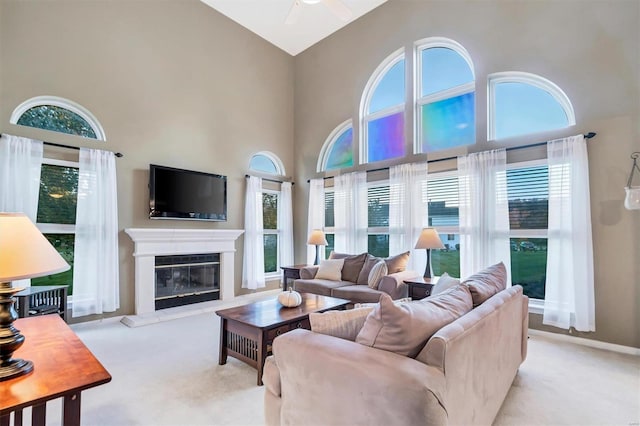 carpeted living room with ceiling fan, high vaulted ceiling, and plenty of natural light