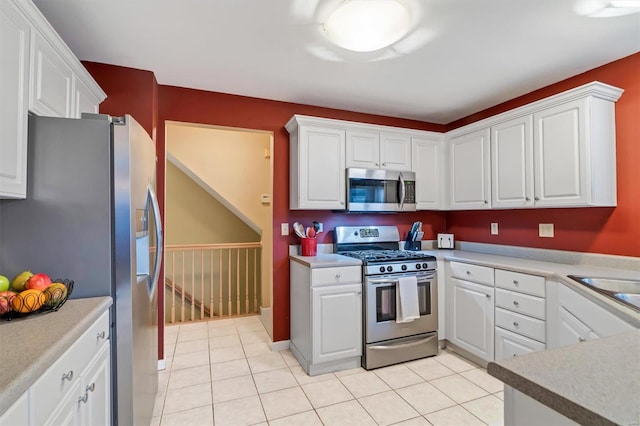 kitchen with appliances with stainless steel finishes, light tile patterned floors, and white cabinets