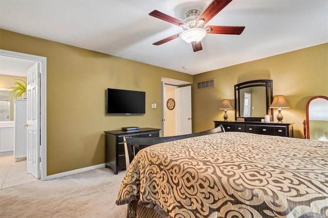 bedroom with light carpet, ensuite bath, and ceiling fan