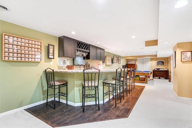 kitchen with hardwood / wood-style floors, a kitchen breakfast bar, kitchen peninsula, and dark brown cabinets