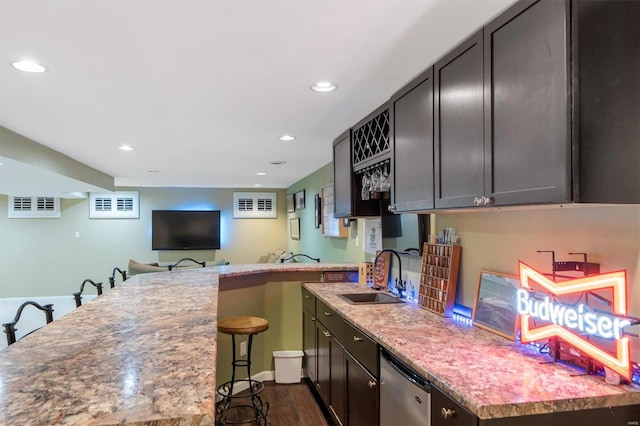 kitchen featuring dishwasher, sink, dark hardwood / wood-style flooring, light stone counters, and a breakfast bar